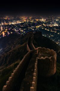 Aerial view of Nahargarh Fort with Jaipur city illuminated at night, showcasing its historic beauty.