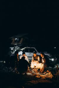 Camping adventure with friends under a starry night sky in Oman, around a cozy campfire.